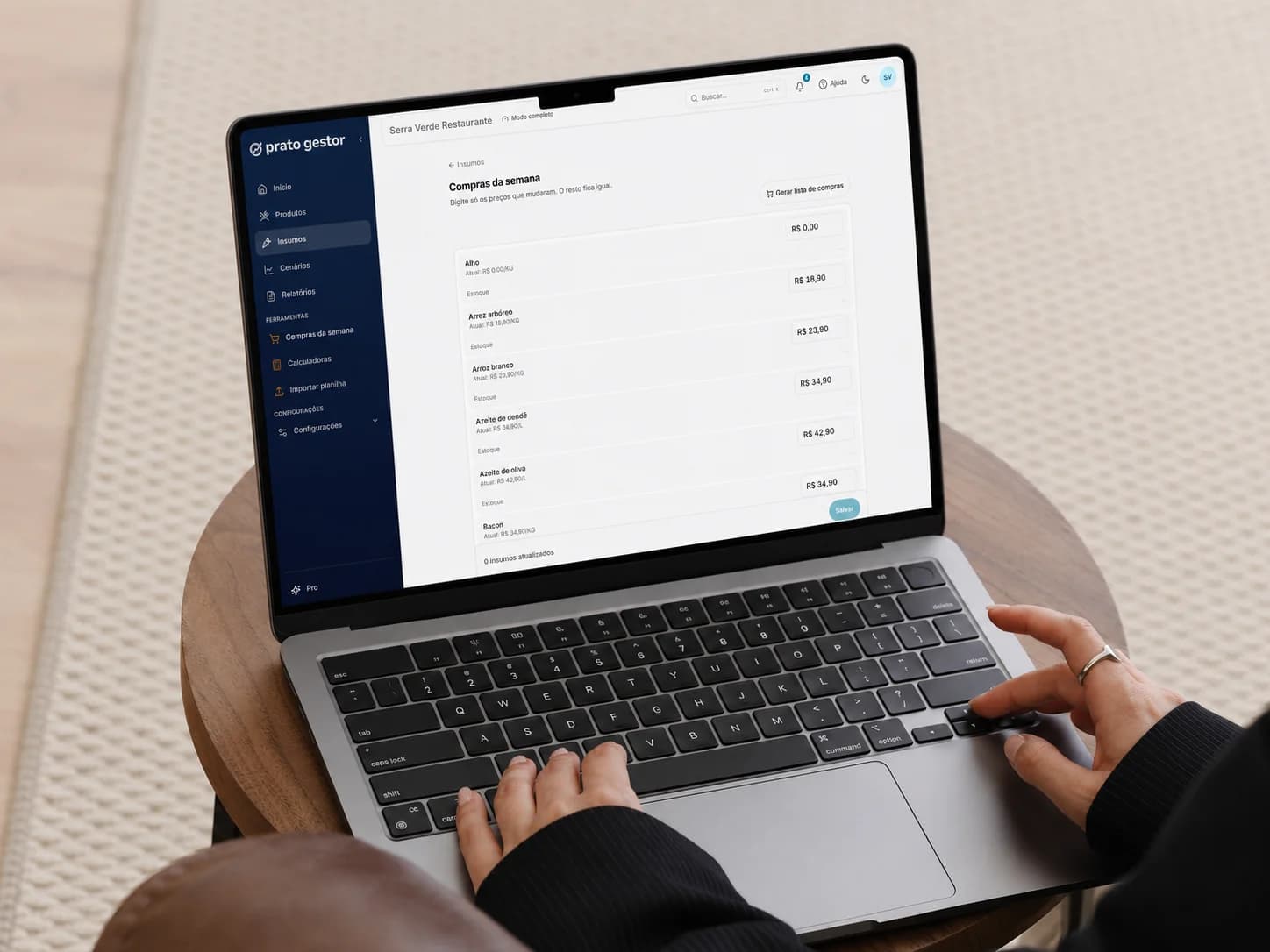 Pessoa usando o Prato Gestor num notebook, com a tela de compras da semana aberta pra atualizar os preços dos insumos